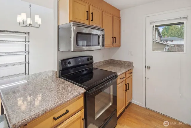 a kitchen with granite countertop a stove and a microwave
