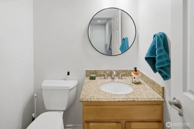 a bathroom with a granite countertop toilet and a sink