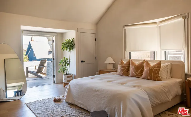a bedroom with a large bed a rug and wooden floor