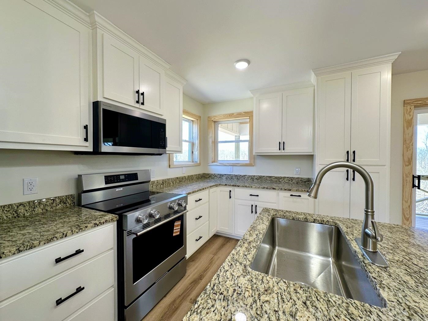 3840 Federal Road Counce, TN 38326 - Photo 11 of 40 Kitchen featuring stainless steel appliances, white cabinetry, wood finished floors, and light stone countertops