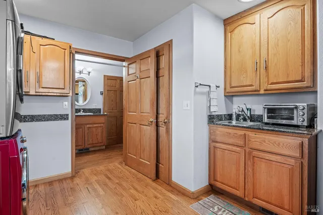 a kitchen with granite countertop a refrigerator a sink and white cabinets
