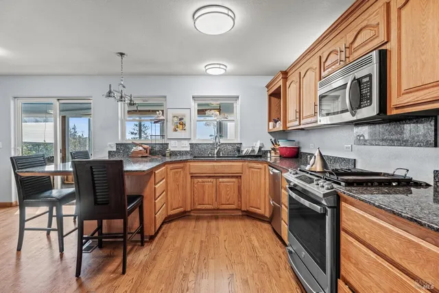 a kitchen with stainless steel appliances granite countertop a stove a sink dishwasher and cabinets with wooden floor