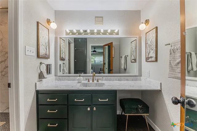 a bathroom with a granite countertop sink vanity and mirror