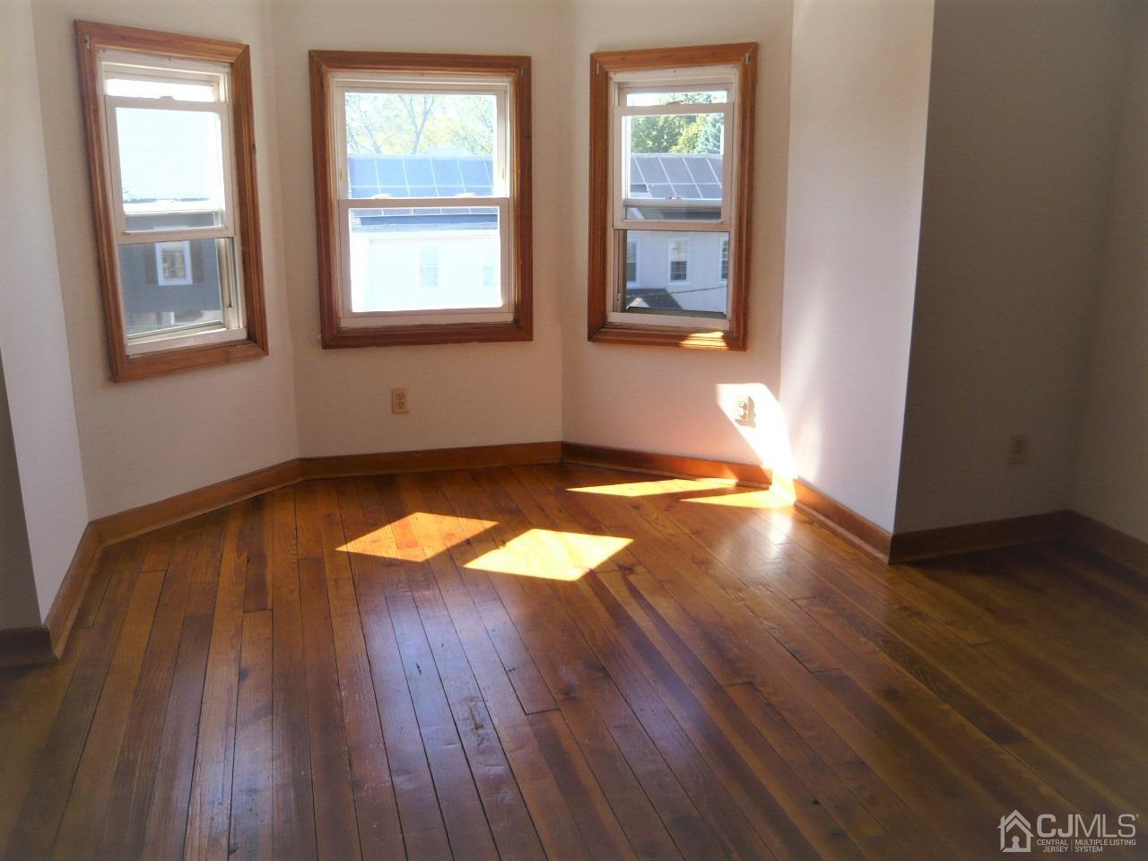 232 Rector Street Perth Amboy, NJ 08861 - Photo 22 of 31 an empty room with wooden floor and windows