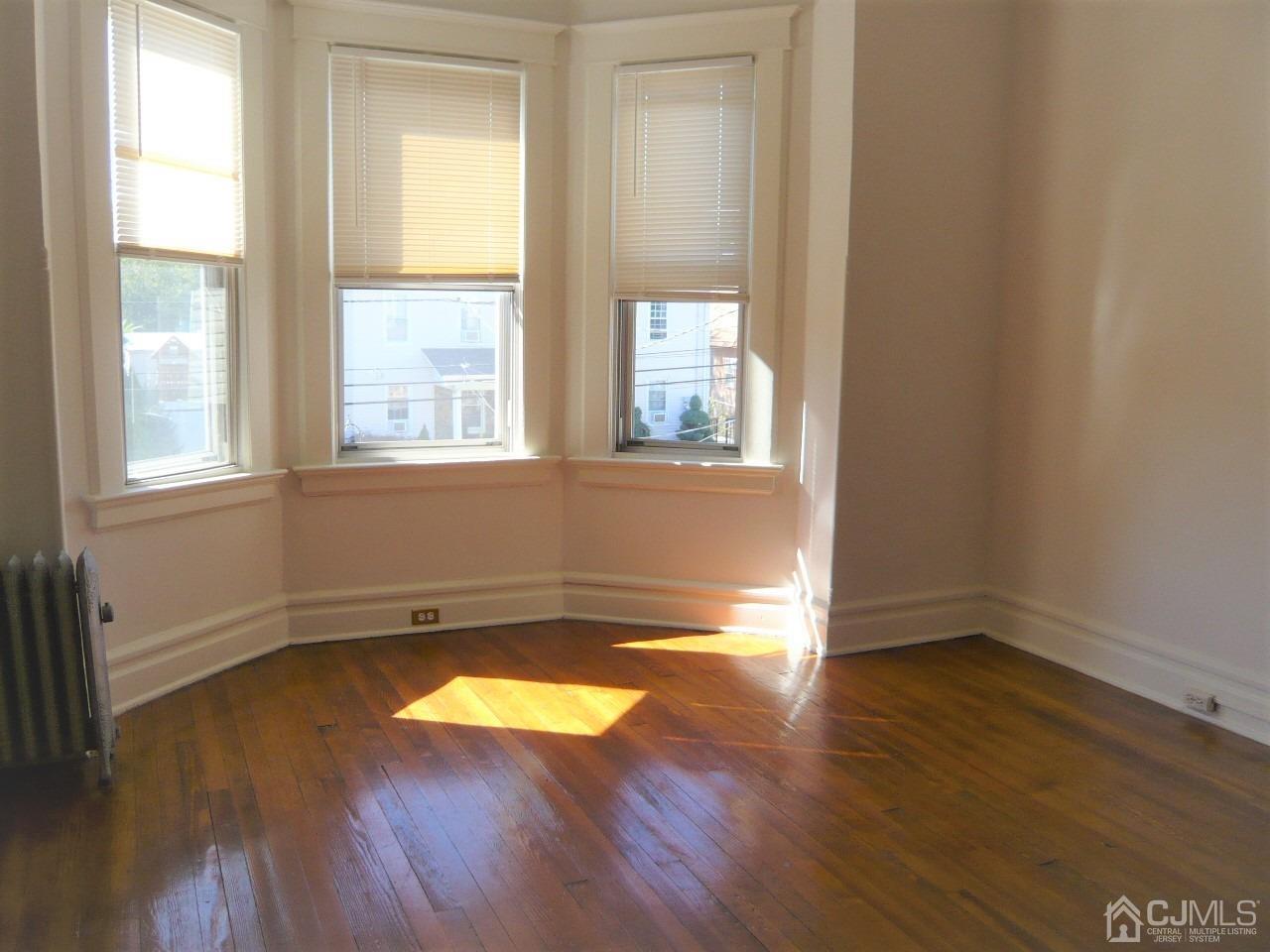 232 Rector Street Perth Amboy, NJ 08861 - Photo 25 of 31 an empty room with wooden floor and windows