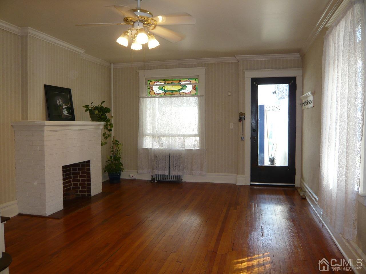 232 Rector Street Perth Amboy, NJ 08861 - Photo 5 of 31 a view of an empty room with wooden floor fireplace and a window