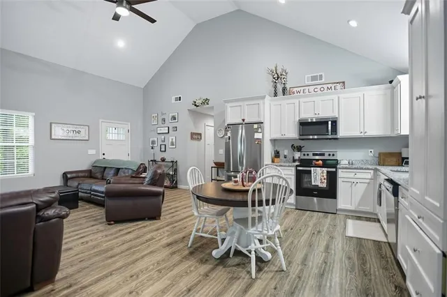 a living room with stainless steel appliances furniture and a wooden floor