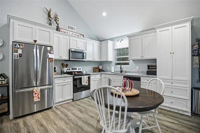 a kitchen with stainless steel appliances granite countertop a refrigerator a stove a sink dishwasher a microwave oven with a dining table and chairs