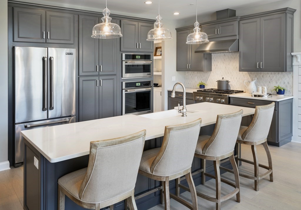 a kitchen with stainless steel appliances kitchen island granite countertop a dining table chairs and a refrigerator