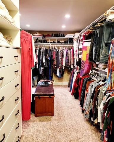 a view of walk in closet with clothes and shoes