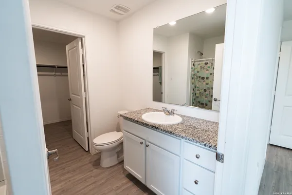 a bathroom with a granite countertop sink a toilet and a mirror