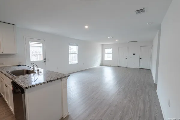 a kitchen with granite countertop a sink a stove and wooden floor