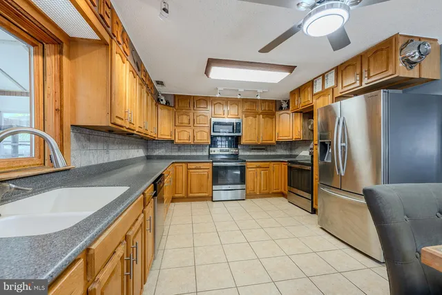 a kitchen with stainless steel appliances granite countertop a sink window and cabinets