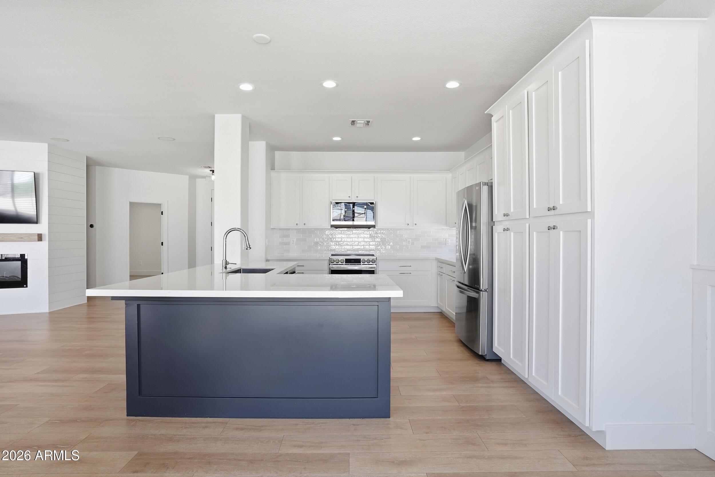 3262 East Cotton Lane Gilbert, AZ 85234 - Photo 13 of 53 a large kitchen with stainless steel appliances a large counter top a stove and a refrigerator