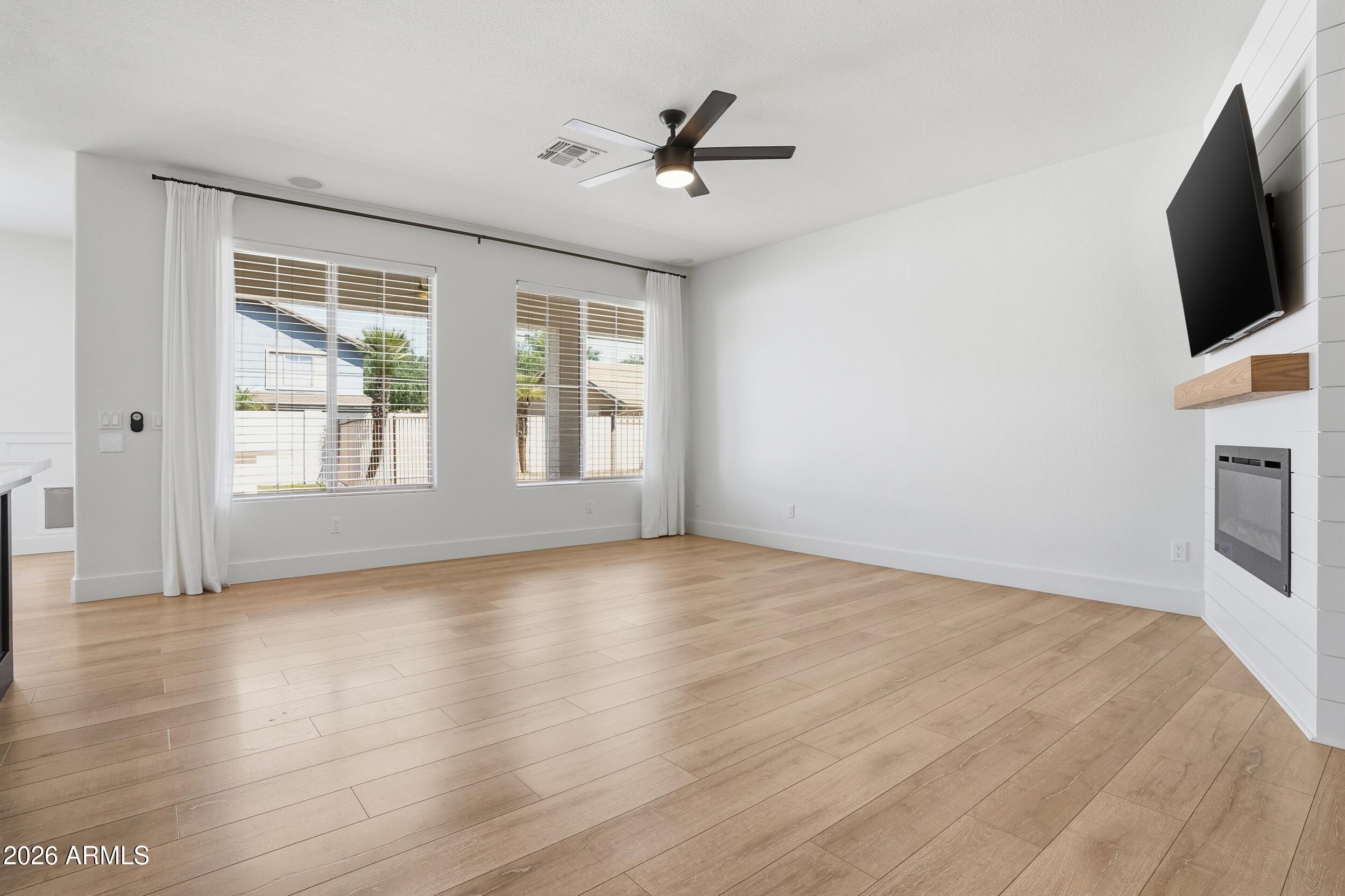 3262 East Cotton Lane Gilbert, AZ 85234 - Photo 6 of 53 a view of a livingroom with a flat screen tv ceiling fan and hardwood floor