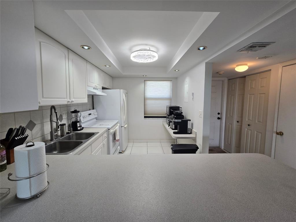 1401 North Riverside Drive, Unit 705 Pompano Beach, FL 33062 - Photo 6 of 30 a kitchen with white cabinets and stainless steel appliances