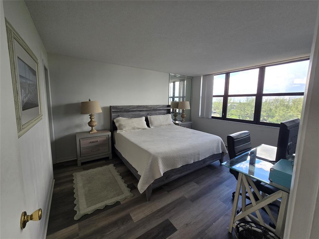 1401 North Riverside Drive, Unit 705 Pompano Beach, FL 33062 - Photo 8 of 30 a bedroom with a bed a table and a large window