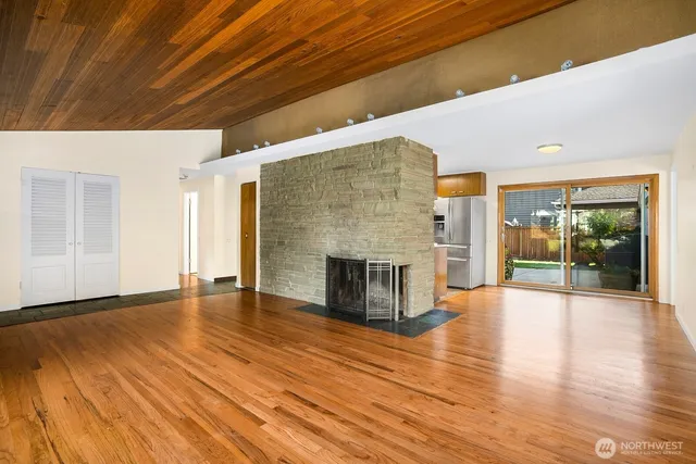 a view of an empty room with wooden floor and a fireplace