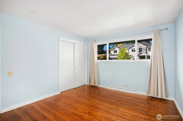 a view of an empty room with window and wooden floor