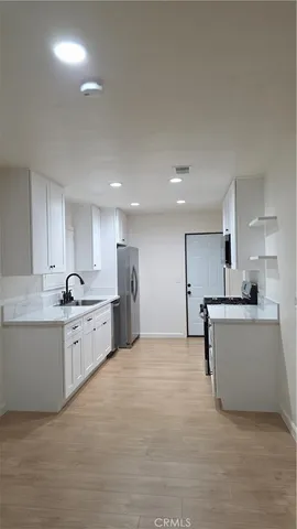 a large white kitchen with a white countertops a stove a sink and a refrigerator