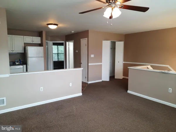 a view of an empty room with window and a kitchen