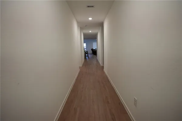a view of a hallway with wooden floor and a bathroom