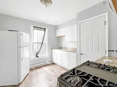 a kitchen with a stove a refrigerator and white cabinets