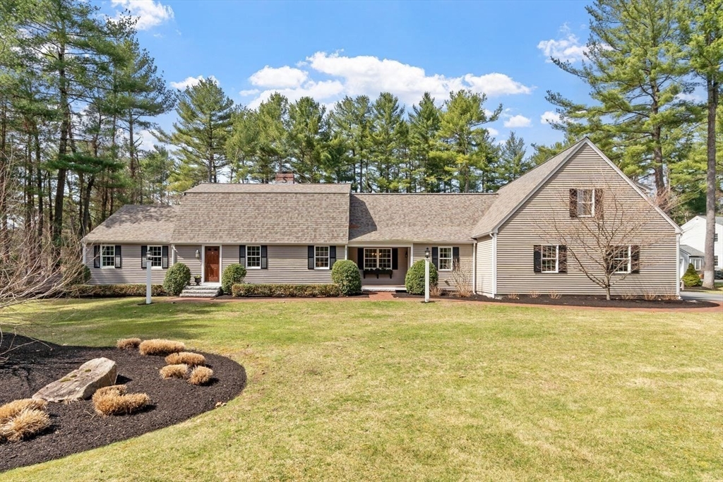 a front view of a house with a garden and trees