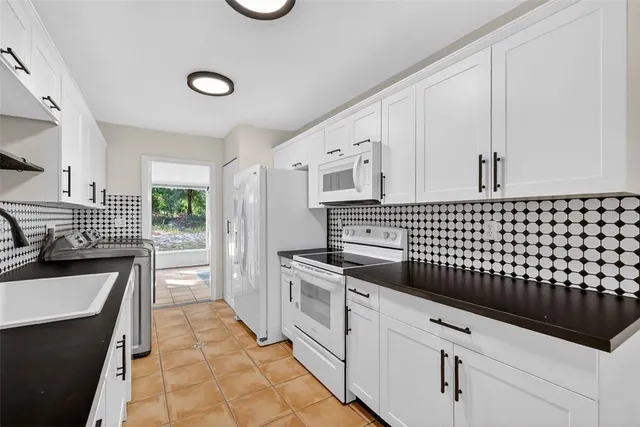 a kitchen with granite countertop a sink a stove oven and white cabinets
