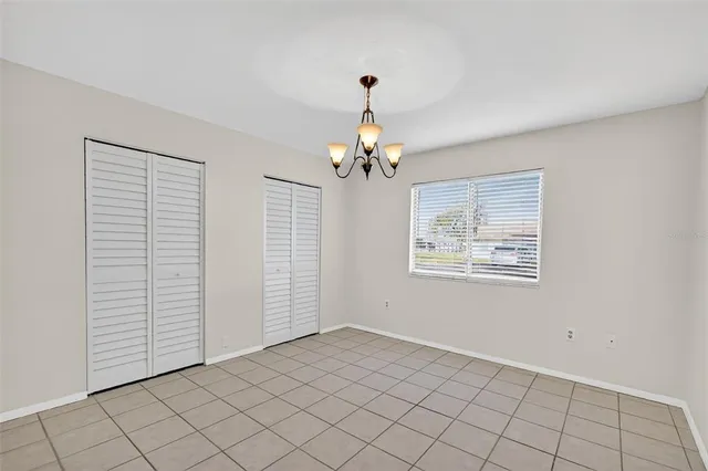 an empty room that has a chandelier fan and window