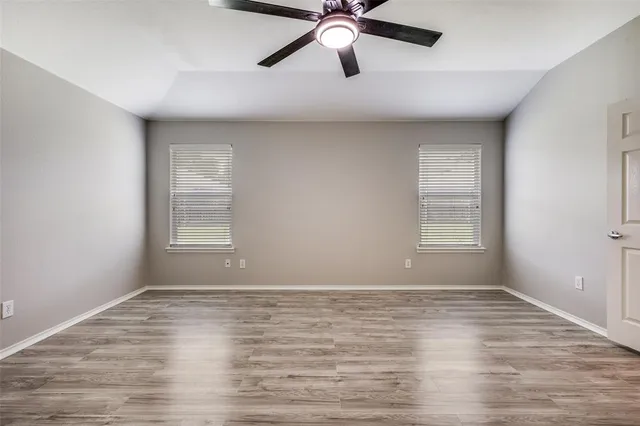 a view of empty room with wooden floor and fan