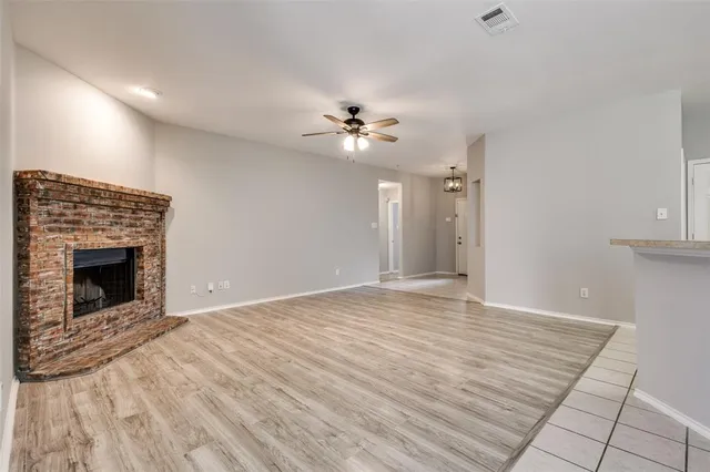 a view of an empty room with a fireplace and a fan