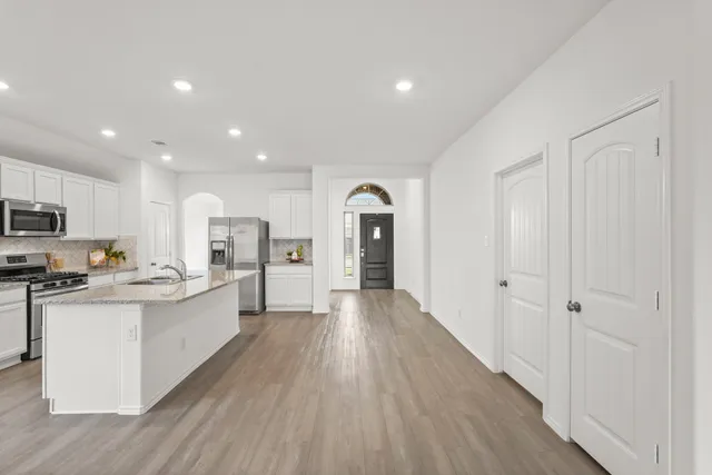 a view of a kitchen with stainless steel appliances wooden floor and wooden cabinets