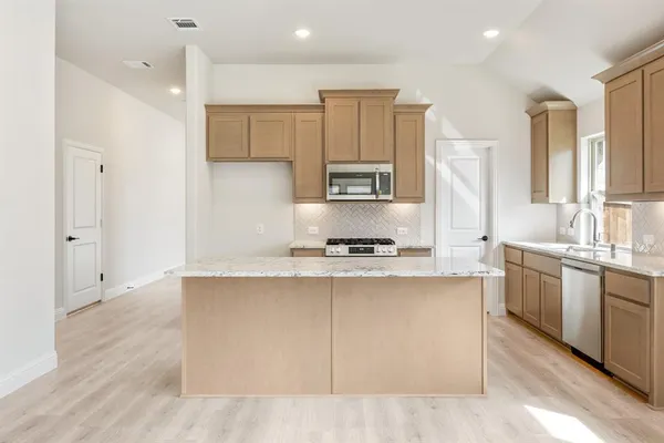 a kitchen with stainless steel appliances granite countertop a sink a stove and a refrigerator