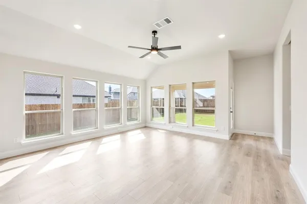 a view of an empty room with a window and wooden floor
