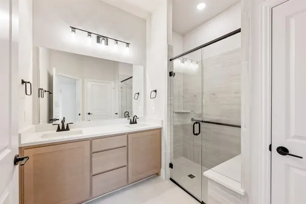 a bathroom with a double vanity sink mirror and shower