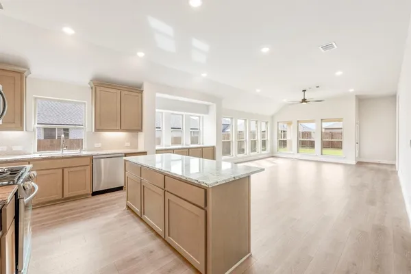 a open kitchen with granite countertop a stove top oven sink and cabinets