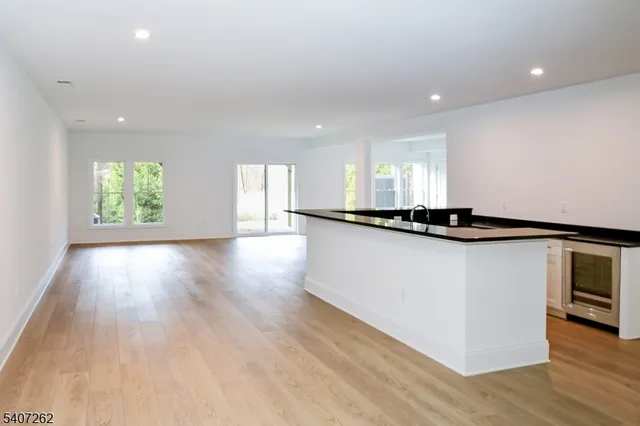 a view of a kitchen with kitchen island a sink wooden floor and a large window