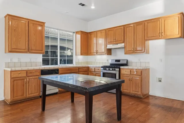 a kitchen with granite countertop a stove a sink dishwasher and cabinets with wooden floor