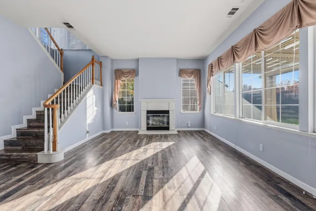 a view of an empty room with wooden floor fireplace and a window