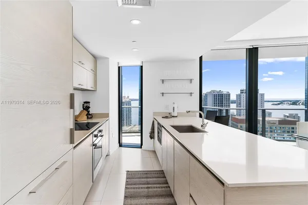 a kitchen with a sink a refrigerator and white cabinets