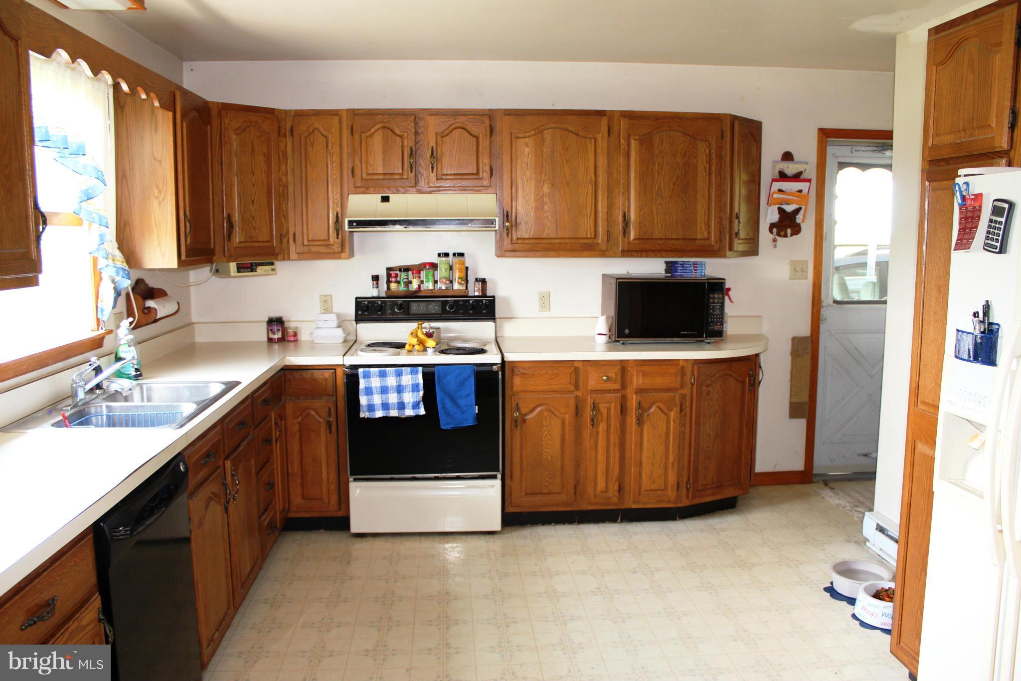 14565 Mercersburg Road Clear Spring, MD 21722 - Photo 11 of 15 a kitchen with stainless steel appliances a stove top oven a refrigerator a sink and dishwasher with wooden cabinets