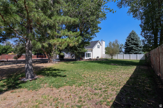 270 East 100 North Monroe, UT 84754 - Photo 43 of 65 Expansive backyard featuring a partial wood fence, a partial white vinyl fence, and mature trees providing natural shade