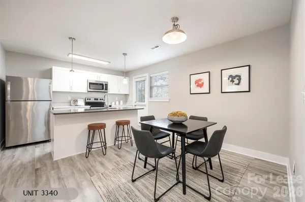 a kitchen with stainless steel appliances granite countertop a dining table chairs refrigerator and sink