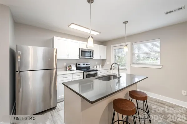a kitchen with stainless steel appliances granite countertop a refrigerator a sink a stove a dining table and chairs