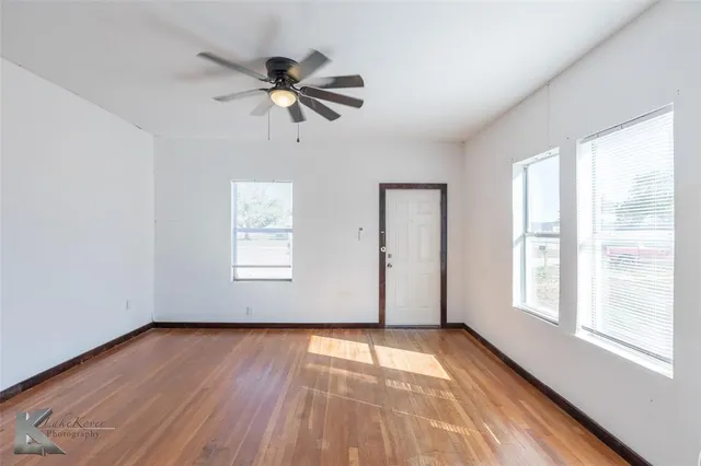 a view of empty room with wooden floor and fan