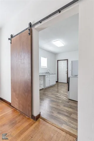 a view of an empty room with wooden floor and a ceiling fan