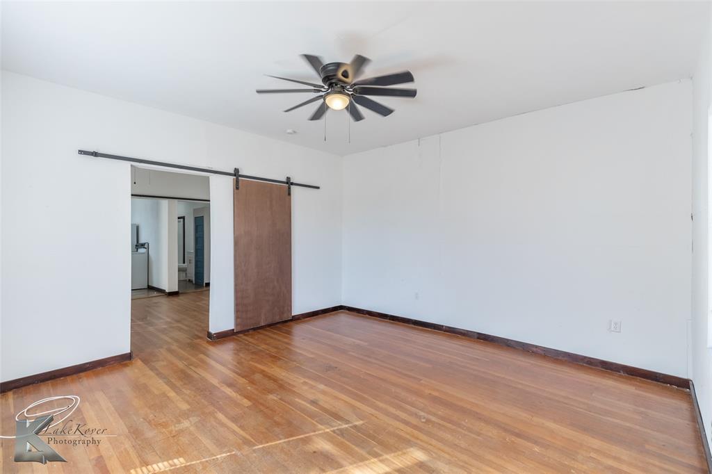 344 Southwest Ave A Hamlin, TX 79520 - Photo 9 of 19 a view of an empty room with wooden floor and a ceiling fan