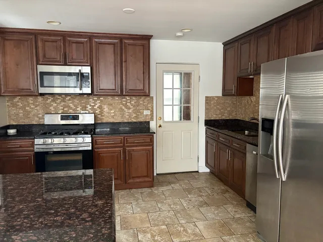 a kitchen with granite countertop a refrigerator and a stove top oven