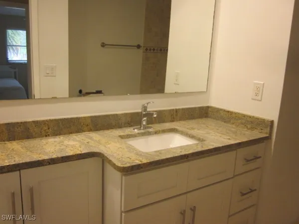 a bathroom with a granite countertop sink and a mirror